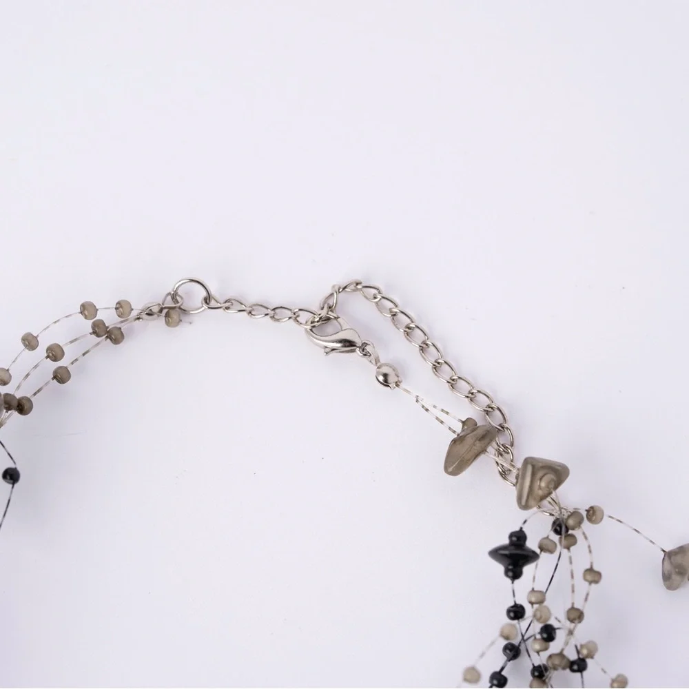 is a multi-strand beaded statement necklace featuring black and‎ grey B4